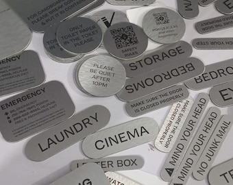 May include: A collection of silver metal signs with black text. Signs include "Recycling", "Laundry", "Cinema", "Emergency", and "Please Be Quiet After 10PM". Other signs provide instructions and safety information.