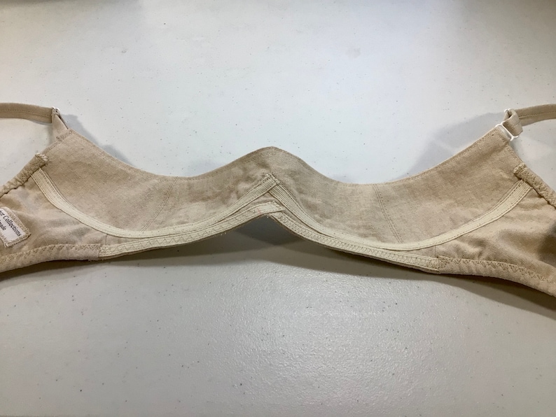 May include: Beige bra with adjustable straps and a hook and eye closure. The bra is made of a soft, comfortable fabric.