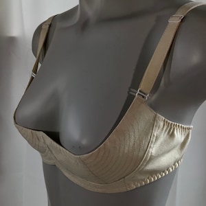 May include: A white satin bra with adjustable straps. The bra has a smooth, seamless design and a low-cut neckline.