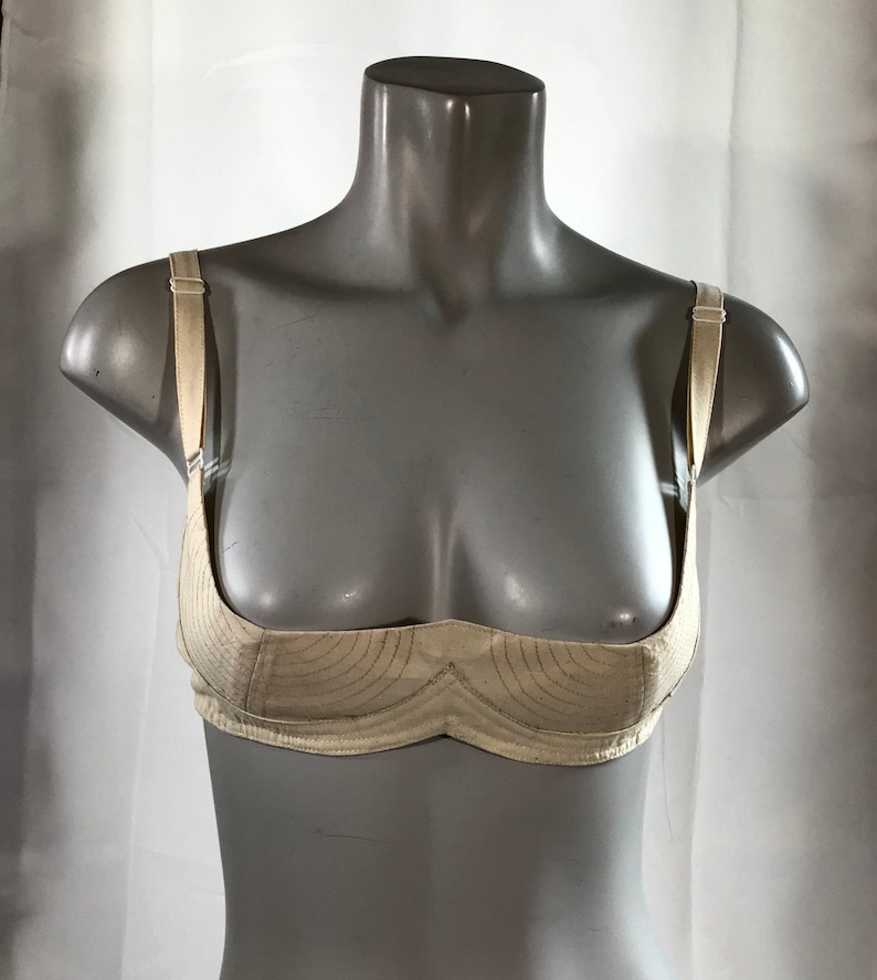 May include: A white, lightly padded bra with adjustable straps. The bra has a simple design with a curved, scalloped neckline.