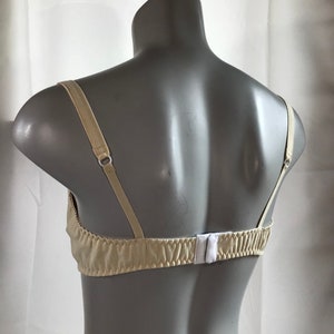 May include: A beige bra with adjustable straps and a hook and eye closure in the back.