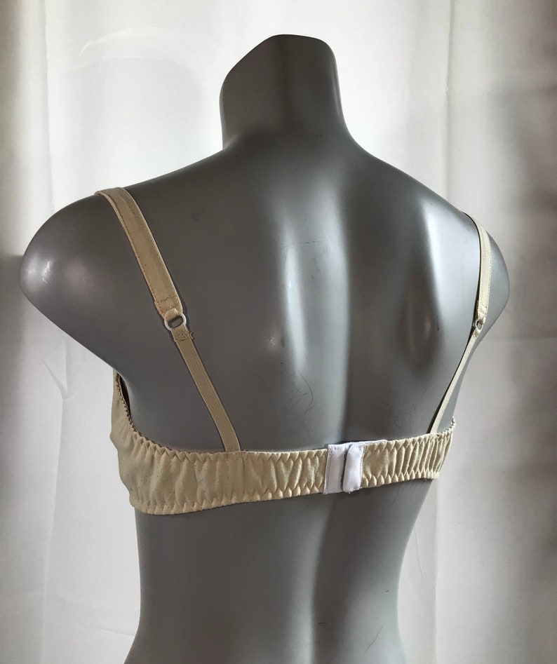 May include: A beige bra with adjustable straps and a hook and eye closure in the back.