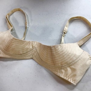 May include: A beige bra with adjustable straps and a lined cup. The bra is made of a soft, breathable fabric and has a comfortable fit.