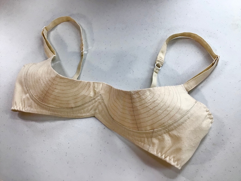 May include: A beige bra with adjustable straps and a lined cup. The bra is made of a soft, breathable fabric and has a comfortable fit.