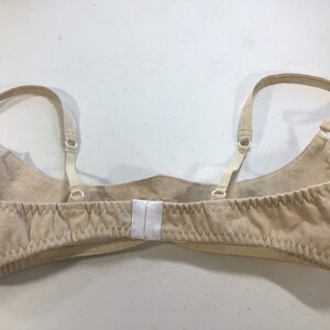 May include: A beige bra with adjustable straps and a hook and eye closure in the back.