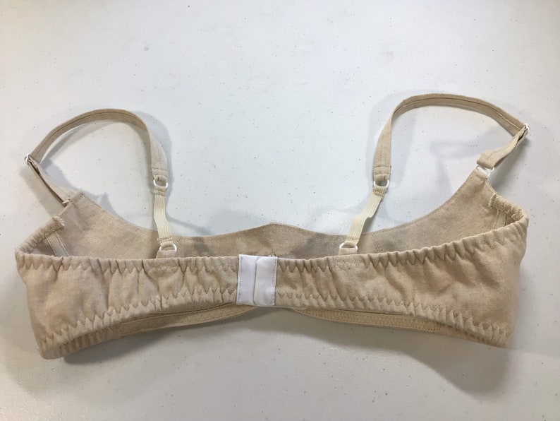 May include: A beige bra with adjustable straps and a hook and eye closure in the back.
