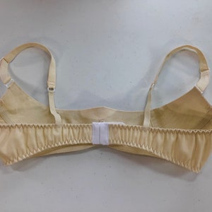 May include: A beige bra with adjustable straps and a hook and eye closure in the back.