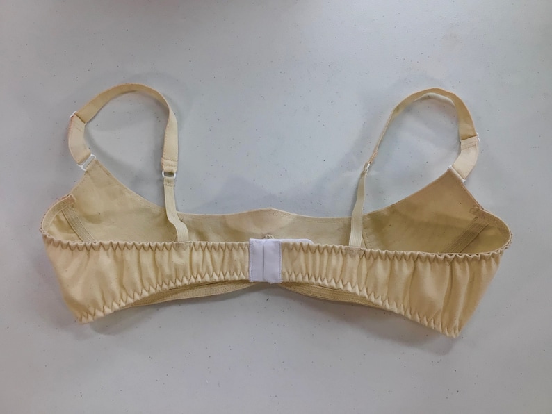 May include: A beige bra with adjustable straps and a hook and eye closure in the back.