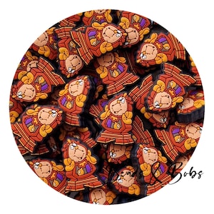 Op de afbeelding: Een verzameling oranje, bruine en gele klokvormige bedels. Elke bedel heeft een lachend gezicht, met paarse en witte details. De bedels zijn in een cirkelvormig patroon gerangschikt, wat een speels en decoratief effect creëert.