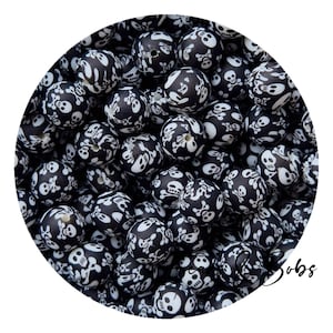 May include: A pile of black beads decorated with white skulls and crossbones. The beads are spherical and have a matte finish. The skulls are white against a black backdrop. Ideal for jewellery making and crafting projects.