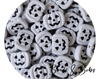 May include: A close-up of a pile of grey silicone pumpkin-shaped beads with black jack-o'-lantern faces. The beads are ideal for making Halloween jewellery or crafts.