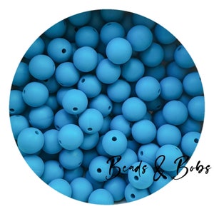 Könnte beinhalten: Eine Ansammlung hellblauer, runder Perlen mit matter Oberfläche. Jede Perle hat ein kleines Loch. Das Bild ist vor einem weißen Hintergrund und enthält den Text "Beads & Bobs" in Schreibschrift.