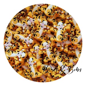 May include: A large group of yellow and black tiger character charms. The charms are made of silicone and have a cartoonish appearance.