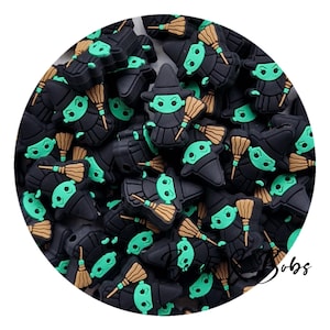 Könnte beinhalten: Eine große Gruppe schwarzer und grüner Hexen-Anhänger mit Besen. Die Anhänger sind aus Silikon und haben ein niedliches Cartoon-Design.