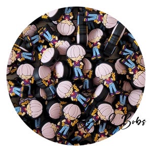 May include: A collection of small, flat, rubberised shoe charms featuring a cartoon character with a light purple bowl-cut hairstyle, a maroon vest, and blue trousers. Each charm depicts the character making a peace sign with one hand.
