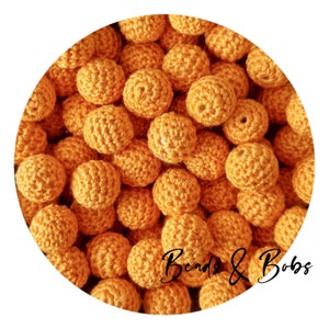May include: A close-up image of a large group of crocheted orange beads. The beads are all the same size and shape, and they are arranged in a random pattern. The beads are soft and fluffy, and they have a slightly textured surface.