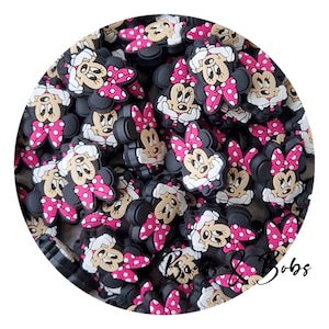 Könnte beinhalten: Eine Sammlung von schwarzen, weißen und rosa Minnie Mouse Schuh-Anhängern. Jeder Anhänger zeigt Minnie's Gesicht, eine rosa Schleife mit weißen Punkten und einen weißen Kragen. Die Anhänger sind kreisförmig angeordnet.