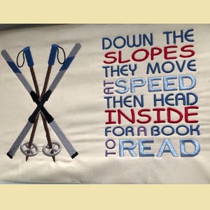 May include: Embroidered design on a white fabric with a pair of crossed ski poles and the text "Down the slopes they move at speed then head inside for a book to read".