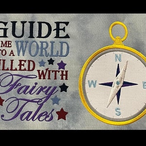 May include: Embroidered design featuring a compass with the text "Guide me to a world filled with fairy tales". The compass is gold with a white face and black needle. The text is in purple, blue, and black.