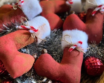 Op de afbeelding: Een mand gevuld met rode kerstsokken van vilt met witte bontkraag en snoepstokaccenten. De sokken zijn omringd door rood en zilver tinsel.