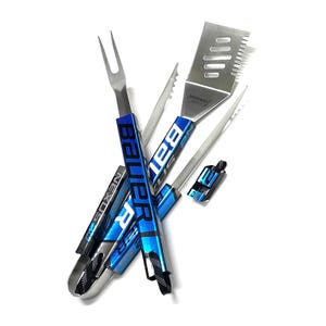 May include: A set of stainless steel grilling tools with blue and black accents. The set includes a spatula, fork, tongs, and a small tool, all featuring the "Bauer" and "Nexus" logos. The tools are designed for outdoor cooking.