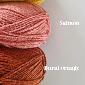 May include: Four skeins of yarn stacked vertically in mustard, salmon, burnt orange, and lime colours. Each skein is labelled with its corresponding colour name in white text to the right of the yarn. The yarn has a visible twisted fibre texture.