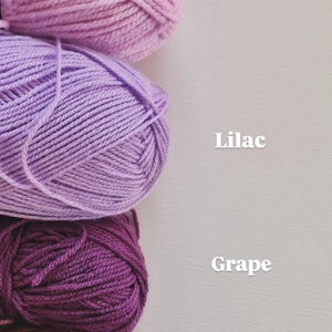 May include: Four skeins of yarn stacked vertically in shades of light pink, light purple, dark purple, and dusty rose. The text labels next to the yarn read Lavendar, Lilac, Grape, and Blush, indicating the specific colour names for each yarn skein.
