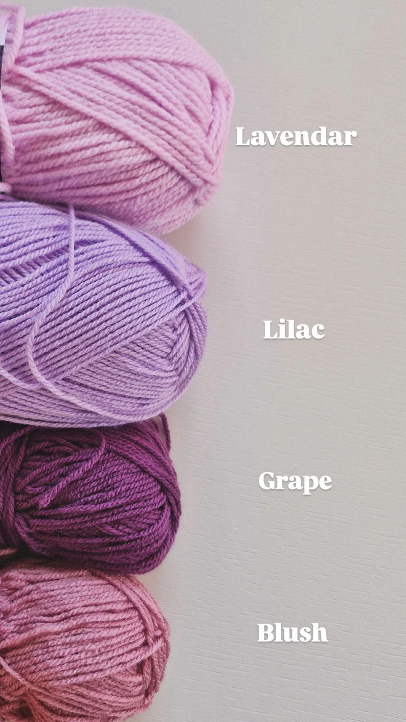 May include: Four skeins of yarn stacked vertically in shades of light pink, light purple, dark purple, and dusty rose. The text labels next to the yarn read Lavendar, Lilac, Grape, and Blush, indicating the specific colour names for each yarn skein.