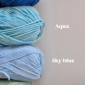 May include: Four skeins of yarn stacked vertically, labelled with text. The top skein is cobalt blue, followed by aqua, sky blue, and sage green. Each yarn ball is clearly identified by the printed text Cobalt, Aqua, Sky blue, and Sage.