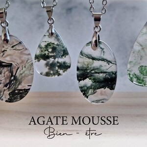 Op de afbeelding: Vier mosagaat hangers aan zilveren kettingen. De hangers hebben groene en bruine insluitsels in een doorschijnende steen. De tekst "AGATE MOUSSE Bien-être" staat onderaan de afbeelding.