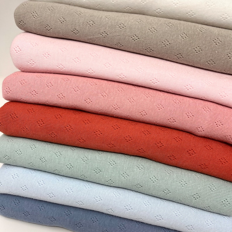 Peut inclure: Un lot de sept &eacute;chantillons de tissu de diff&eacute;rentes couleurs, dont le beige, le rose, le rouge, le vert et le bleu. Le tissu a une texture &agrave; armure ouverte.