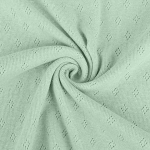 Peut inclure: Un gros plan sur un tissu vert clair avec un motif en forme de diamant. Le tissu est doux et a une surface l&eacute;g&egrave;rement textur&eacute;e.