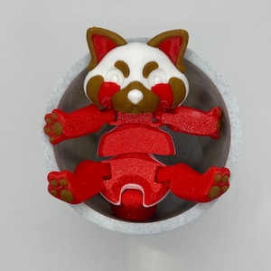 May include: A red and white articulated toy red panda in a white ceramic bowl. The toy has brown ears and paws.