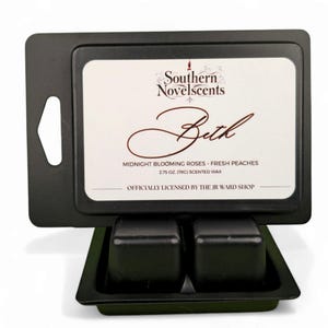 May include: A black scented wax melt warmer with two cubes of wax. The label reads "Southern Novelscents Beth" with scent notes of Midnight Blooming Roses and Fresh Peaches. The wax is 2.75 oz.