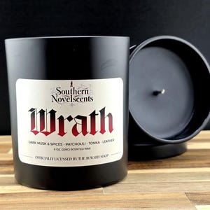 May include: A black scented candle with a white label featuring the word "Wrath" in red gothic lettering. The label also includes the scent description: Dark Musk & Spices, Patchouli, Tonka, and Leather. The candle is 8 oz (226g).