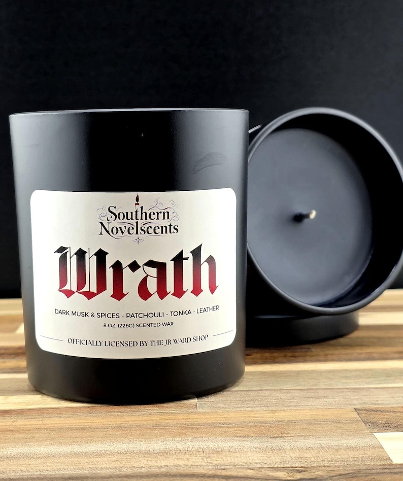 May include: A black scented candle with a white label featuring the word "Wrath" in red gothic lettering. The label also includes the scent description: Dark Musk & Spices, Patchouli, Tonka, and Leather. The candle is 8 oz (226g).