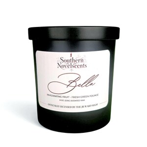以下が含まれることがあります： 白ラベルの黒いアロマキャンドル。ラベルには「Southern Novelscents Bella」と「Invigorating Fruit - Fresh Green Foliage」と記載されています。キャンドルは226gで、公式ライセンス商品です。