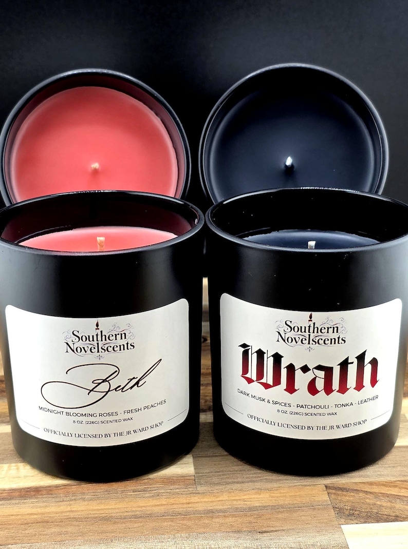 May include: Two black scented candles with lids off, revealing red and dark blue wax. The labels read "Beth" and "Wrath" with scent descriptions. The candles are 8 oz (226g) each.