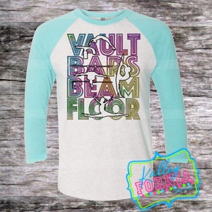 May include: A white and light gray raglan shirt with turquoise sleeves. The shirt features the words "VAULT BARS BEAM FLOOR" in a colorful, outlined font, with gymnast figures integrated into the letters. The shirt has a crew neck.
