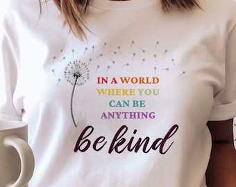 May include: White t-shirt featuring a dandelion graphic and the text "In a world where you can be anything be kind". The text is in rainbow colours.