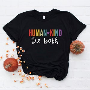 May include: Black t-shirt with the text "HUMAN-KIND Be both" in rainbow colors with a heart symbol between the words "HUMAN" and "KIND".