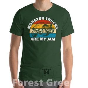 May include: A forest green t-shirt with a vintage-style graphic of a monster truck. The graphic features a red, orange, yellow, and blue color scheme. The text on the shirt reads "Monster Trucks Are My Jam".