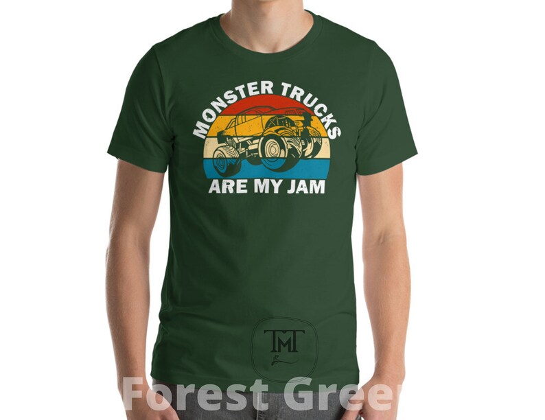 May include: A forest green t-shirt with a vintage-style graphic of a monster truck. The graphic features a red, orange, yellow, and blue color scheme. The text on the shirt reads "Monster Trucks Are My Jam".