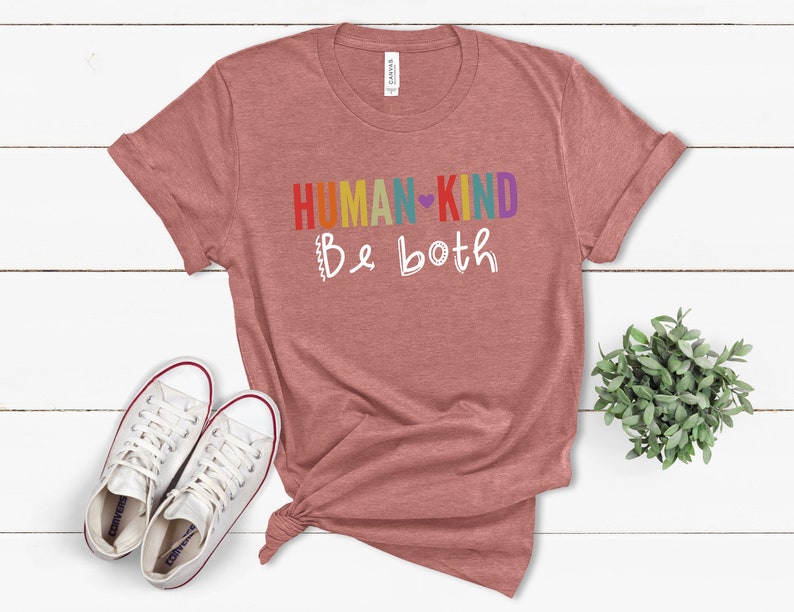 Puede incluir: Una camiseta de color rojo heather con el texto "HUMAN-KIND Be both" en colores arco&iacute;ris y un coraz&oacute;n blanco.