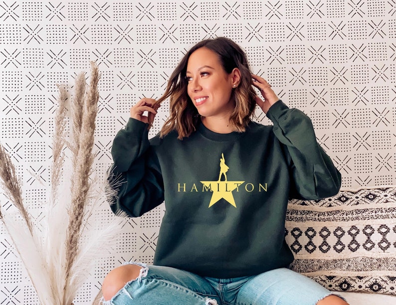 May include: A dark green sweatshirt with a yellow star and the word "HAMILTON" printed on the front.