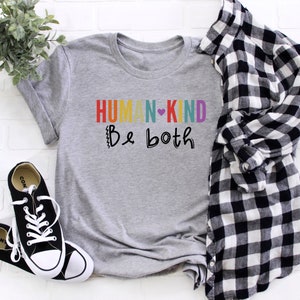 Puede incluir: Camiseta gris con el texto "HUMAN-KIND Be both" en colores arco&iacute;ris con un coraz&oacute;n entre las palabras.