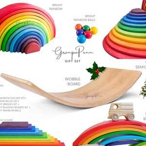 Puede incluir: Un juego de juguetes de madera con un apilador de arco&iacute;ris, bolas de arco&iacute;ris, semic&iacute;rculos, puentes y una tabla oscilante. El juego incluye un cami&oacute;n de madera y tableros de construcci&oacute;n. Los colores son brillantes.