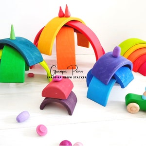 May include: A rainbow-colored wooden arch set with a green car and a small wooden figure. The set is made of natural wood and is perfect for imaginative play.