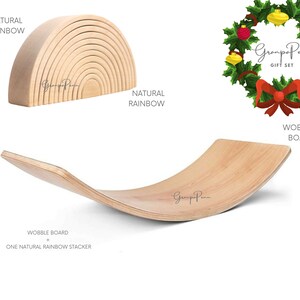 Puede incluir: Un apilador de arco&iacute;ris de madera y una tabla oscilante de madera curvada. El apilador de arco&iacute;ris est&aacute; hecho de m&uacute;ltiples piezas arqueadas. La tabla oscilante es curva y tiene un acabado de madera natural. La imagen tambi&eacute;n incluye una corona navide&ntilde;a.