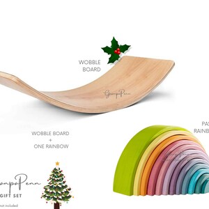 Puede incluir: Un juego de juguetes que incluye una tabla oscilante de madera y un arco&iacute;ris pastel. La tabla oscilante es curva y est&aacute; hecha de madera clara. El apilador de arco&iacute;ris presenta varios colores pastel. El texto de la imagen dice "WOBBLE BOARD + ONE RAINBOW" y "GrampaPenn GIFT SET".